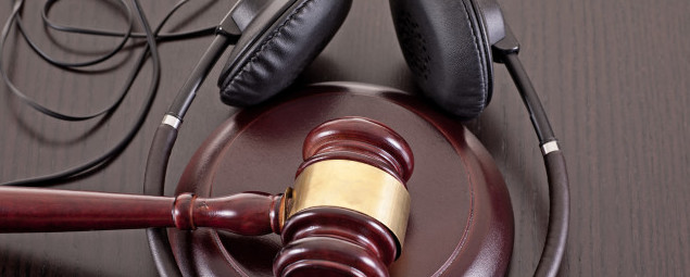 Concept image about music piracy and copyright protection law featuring  a gavel and headphones on tabletop